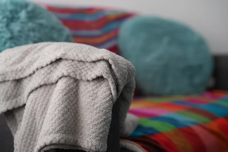 Soft grey blankets and teal cushions on the Rainbow Room sofa